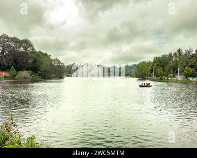 Kodaikanal, Tamil Nadu. India - 16 dicembre 2023: Vista panoramica del lago kodaikanal con fontana e gente che si gode un giro in barca. Foto Stock