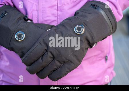 Donna che indossa guanti riscaldati a batteria durante le basse temperature. I guanti hanno impostazioni di calore variabili e aiutano coloro che soffrono di malattia di Reynauds Foto Stock
