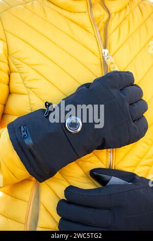 Donna che indossa guanti riscaldati a batteria durante le basse temperature. I guanti hanno impostazioni di calore variabili e aiutano coloro che soffrono di malattia di Reynauds Foto Stock