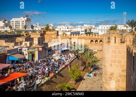 Guardando in basso un tradizionale mercato di abbigliamento all'aperto accoccolato accanto al Ribat e alle antiche mura della medina a Sousse, in Tunisia. Foto Stock