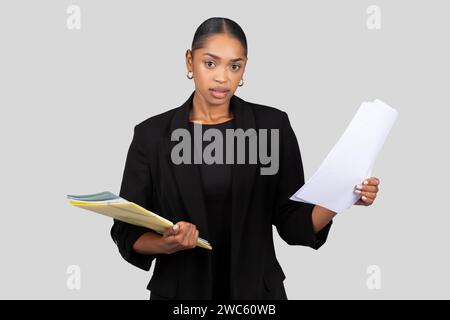 Seria donna d'affari afroamericana in possesso di documenti e una cartella Foto Stock