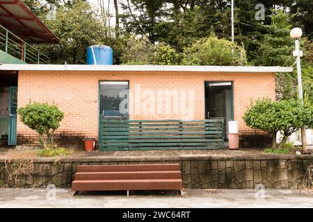 Edificio in mattoni rossi in disuso e abbandonato con due porte in vetro con scale in metallo che conducono al passaggio pedonale in cemento Foto Stock