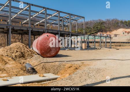 Chungju, Corea del Sud, 22 marzo 2020: Solo per uso editoriale. Grande serbatoio rotondo a terra davanti all'edificio con telaio in metallo non finito in campagna Foto Stock