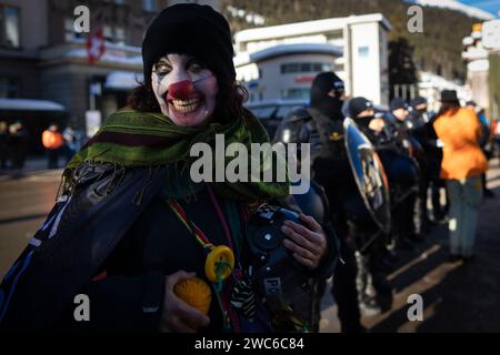 Davos, Svizzera. 14 gennaio 2024. Davos, CH 14 gennaio 2024. Un manifestante vestito da clown viene fermato da un cordone della polizia durante il 54° Forum economico Mondiale. Centinaia di manifestanti si sono riuniti per esprimere preoccupazioni sull'agenda del WEF di quest'anno. Il Forum coinvolge i leader politici, commerciali e culturali della società per definire i programmi globali, regionali e industriali, che possono avere un impatto su tutti in tutto il mondo. Crediti: Andy Barton/Alamy Live News Foto Stock