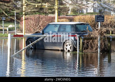 Wallingford, Oxfordshire, Regno Unito. 14 gennaio 2024. Il fiume Tamigi a Wallingford, Oxfordshire, è scoppiato questa settimana e ha inondato il Riverside Car Park. Alcune auto erano completamente sommerse dalle acque alluvionali. Un mini polo VW attendono il recupero. Credito: Maureen McLean/Alamy Live News Foto Stock