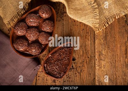 Uova di Pasqua al cioccolato ripiene di brigatieri su sfondo rustico in legno. Foto Stock