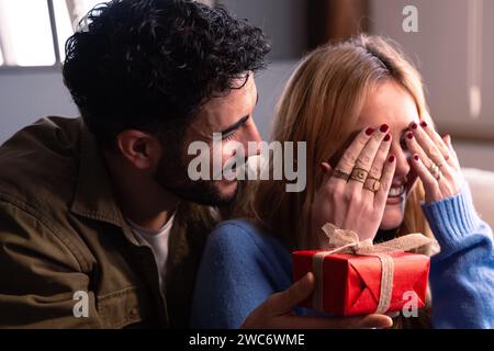 Un giovane sorprende la sua ragazza dandole un regalo in una scatola rossa. Festa di San Valentino. Foto Stock