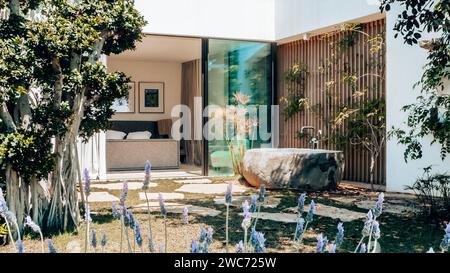Un giardino splendidamente paesaggistico circonda una casa affascinante, che presenta una suggestiva disposizione di grandi rocce collocate strategicamente nella parte anteriore Foto Stock