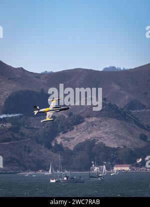 Un jet d'epoca T-33 vola a San Francisco durante uno spettacolo aereo presso il Golden Gate Bridge con le Marin Headlands e le barche a vela sullo sfondo Foto Stock