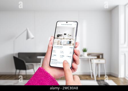 Le mani di una donna con uno smartphone che visualizza un'app immobiliare residenziale. Tecnologia moderna, ricerca di un vero e proprio hotel senza soluzione di continuità e conveniente Foto Stock