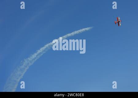 Mar del Plata, Argentina - 14 gennaio 2023: Aereo biplano che fa acrobazie nel cielo e rilascia fumo. Foto Stock