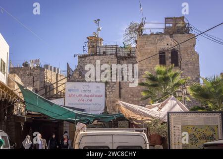 Il popolo palestinese che cammina nel centro di Hebron, sulla sponda occidentale (Palestina) con i vecchi edifici in pietra e insegna "Benvenuti nella città vecchia di Hebron" (in Foto Stock