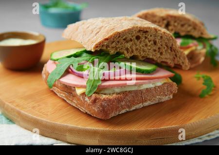 Gustosi panini con salsiccia bollita, cetriolo e rucola sul tavolo, primo piano Foto Stock
