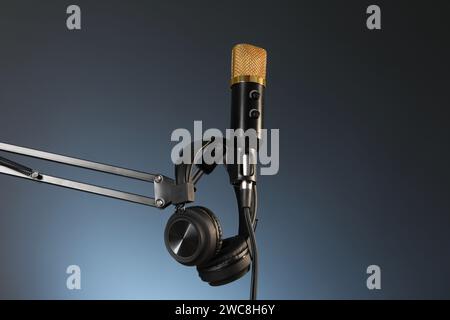 Piedistallo con microfono e cuffie su sfondo scuro, visuale dall'angolo basso. Registrazione audio e potenziamento Foto Stock