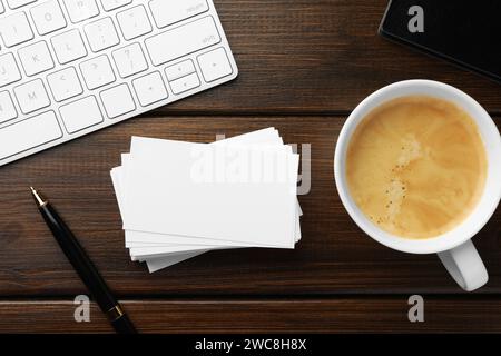 Biglietti da visita vuoti, caffè, tastiera e penna su un tavolo di legno, piano. Mockup per il design Foto Stock
