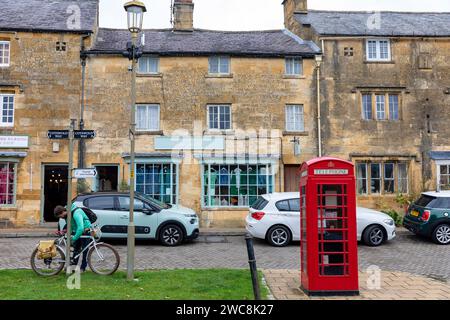 Chipping Campden High Street, uomo che incatena la bicicletta a un lampione, Cotswolds, Inghilterra, Regno Unito, 2023 Foto Stock