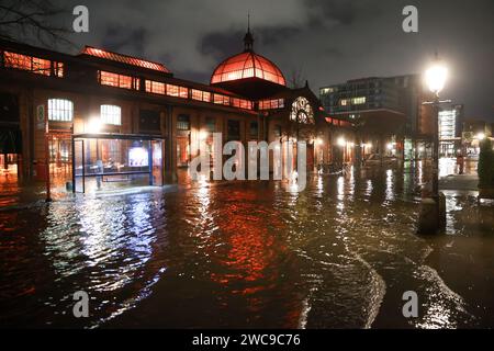 Amburgo, Germania. 15 gennaio 2024. L'acqua dell'Elba viene spinta sul Große Elbstraße al mercato del pesce di Amburgo durante un'ondata di tempesta. Lunedì mattina, l'ondata di tempesta ha spinto ancora una volta molta acqua a riva sulla costa del Mare del Nord e nei fiumi Elba e Weser. Ad Amburgo, il mercato del pesce e il Große Elbstraße erano completamente sott'acqua. Secondo la Federal Maritime and Hydrographic Agency (BSH), l'acqua al St. La sagoma di Pauli era salita a circa 2,30 metri sopra l'acqua media poco prima delle 7,00 del mattino. Credito: Bodo Marks/dpa/Alamy Live News Foto Stock