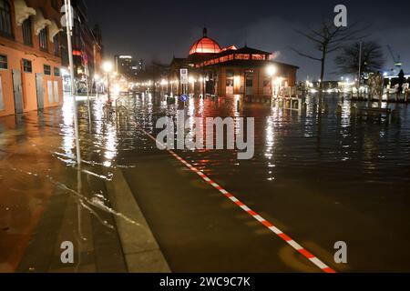 Amburgo, Germania. 15 gennaio 2024. L'acqua dell'Elba viene spinta sul Große Elbstraße al mercato del pesce di Amburgo durante un'ondata di tempesta. Lunedì mattina, l'ondata di tempesta ha spinto ancora una volta molta acqua a riva sulla costa del Mare del Nord e nei fiumi Elba e Weser. Ad Amburgo, il mercato del pesce e il Große Elbstraße erano completamente sott'acqua. Secondo la Federal Maritime and Hydrographic Agency (BSH), l'acqua al St. La sagoma di Pauli era salita a circa 2,30 metri sopra l'acqua media poco prima delle 7,00 del mattino. Credito: Bodo Marks/dpa/Alamy Live News Foto Stock