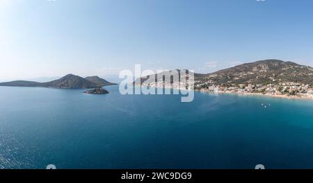 Grecia, Tolo vicino a Nafplio, Argorida, Peloponneso. Vista panoramica aerea con drone del villaggio, piccola isola, barca ormeggiata al porto, mare, cielo blu. Spazio Foto Stock