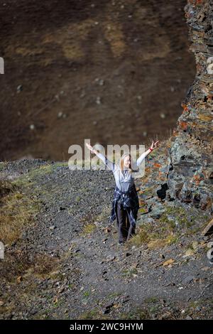 Ragazza felice in cima a una montagna, che si gode la vista, che si estende le braccia ai lati. Foto Stock