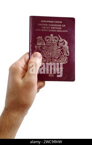 Primo piano sulla mano di un uomo con un passaporto britannico su sfondo bianco. Foto Stock