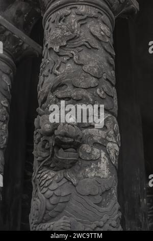 Intricato drago in sculture nuvole su un antico pilastro di pietra presso lo storico sito della Tomba di Khai Dinh, Vietnam Foto Stock