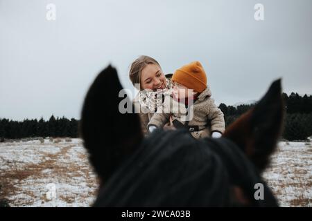 La mamma tiene il bambino a cavallo, assaporando la loro giocosa corsa Foto Stock