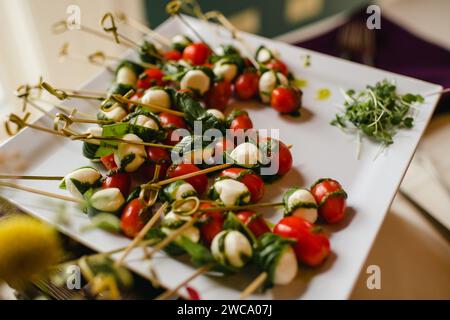 Spiedini caprese con pomodori, mozzarella e basilico su piatto da portata Foto Stock