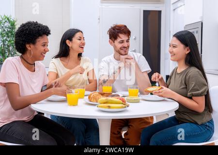 Un gruppo eterogeneo di amici condivide una deliziosa colazione in un ambiente moderno e luminoso Foto Stock