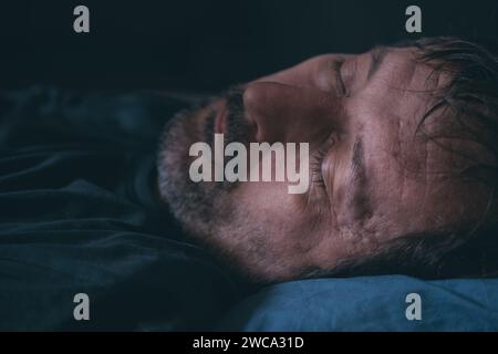 Uomo che dorme a letto, primo piano del viso, messa a fuoco selettiva Foto Stock