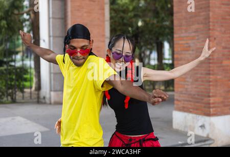 "Due ballerini in armonia, che mostrano la loro passione per la danza a braccia aperte e passi sincronizzati in un abbigliamento urbano casual." Foto Stock