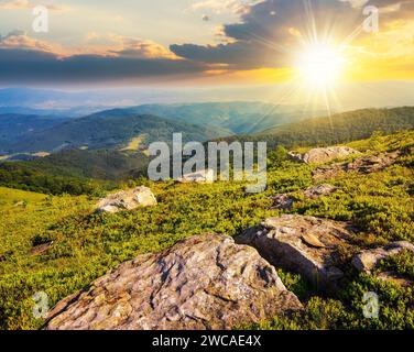 paesaggio montano al tramonto. paesaggio con pietre sul fianco della collina. valle lontana tra colline boscose alla luce della sera Foto Stock