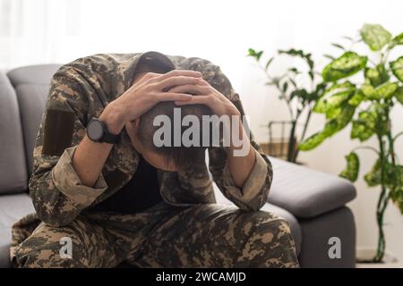 Un soldato sconvolto che gli copre la faccia, forse soffre di shock da conchiglia o disturbo da stress post traumatico Foto Stock