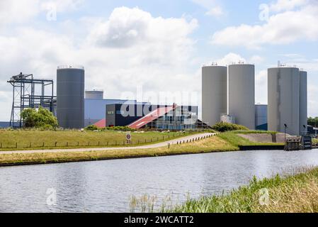Fabbrica con serbatoi di stoccaggio e silos lungo un canale in una giornata estiva parzialmente nuvolosa Foto Stock