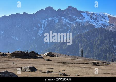 I visitatori camminano lungo il campo asciutto e senza neve durante una giornata invernale soleggiata nella stazione di Sonamarg Hill, a circa 100 km da Srinagar. Un lungo periodo di secchezza si sta diffondendo attraverso la valle del Kashmir durante la fase più dura dell'inverno. Località turistiche come Gulmarg, Pahalgam e Sonamarg avrebbero in genere accumulato un'ampia neve ormai. Ma quest'anno, la valle del Kashmir è asciutta, senza neve da nessuna parte. Mentre il settore turistico è stato colpito duramente, mentre i turisti, che avevano programmato di visitare la Valle a gennaio per godersi la neve, stanno cancellando i loro viaggi. Foto Stock