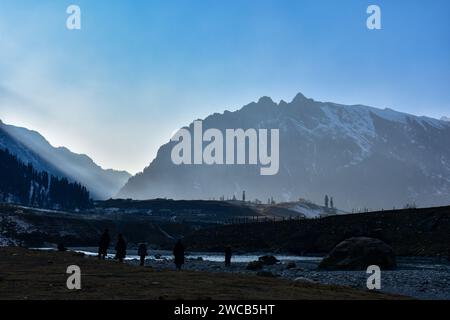 I visitatori camminano lungo il campo asciutto e senza neve durante una giornata invernale soleggiata nella stazione di Sonamarg Hill, a circa 100 km da Srinagar. Un lungo periodo di secchezza si sta diffondendo attraverso la valle del Kashmir durante la fase più dura dell'inverno. Località turistiche come Gulmarg, Pahalgam e Sonamarg avrebbero in genere accumulato un'ampia neve ormai. Ma quest'anno, la valle del Kashmir è asciutta, senza neve da nessuna parte. Mentre il settore turistico è stato colpito duramente, mentre i turisti, che avevano programmato di visitare la Valle a gennaio per godersi la neve, stanno cancellando i loro viaggi. Foto Stock