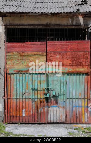 239 porta chiusa di un impianto industriale con tetto in fibra di cemento in una strada della città. Permet-Albania. Foto Stock