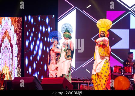 Gruppo di artisti punjabi del punjab che si esibiscono con bhangra in abiti colorati tradizionali al festival dei cammelli bikaner con sorriso e divertimento. Foto Stock