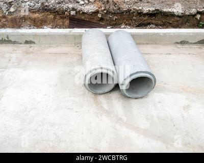 Il nuovo tubo AC (tubi in cemento amianto) sulla strada in cemento per l'uso come tubi di drenaggio intorno al cantiere della stazione ferroviaria, vista frontale f Foto Stock