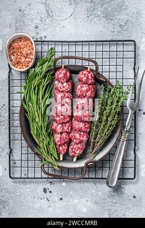 Kebab di Urfa Turco crudo decorato con erbe, spezie e forchetta di carne. Sfondo grigio. Vista dall'alto. Foto Stock