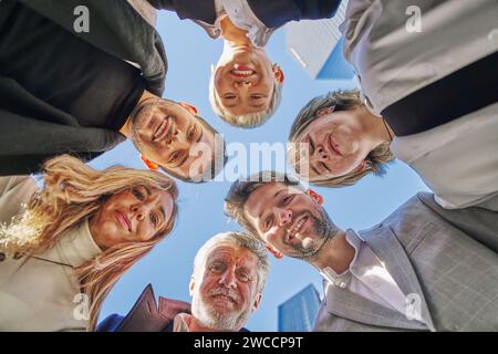 Ritratto ravvicinato vista dal basso volti felici del team di diversi dipendenti in cerchio, guardando la fotocamera, sorridenti donne d'affari e uomini d'affari Foto Stock