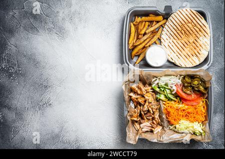 Doner kebab Shawarma su un piatto con patatine fritte e insalata in scatola per andare, da asporto. Sfondo bianco. Vista dall'alto. Spazio di copia. Foto Stock