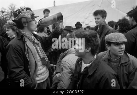 1980s UK Group Teenager Boys ai Badminton Horse Trials. Ragazzo che beve sidro da una bottiglia e con mascotte di orso fissata al suo cappello marrone fedora. Badminton, Gloucestershire, Inghilterra maggio 1985 HOMER SYKES Foto Stock