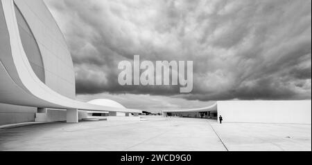 Panorama in bianco e nero dell'architettura moderna del Niemeyer Centre con un uomo a distanza per ingrandire gli edifici, Aviles, Asturie, Spagna Foto Stock