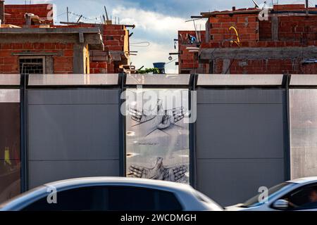 Complexo da Mare, un'enorme rete di favelas che si trova accanto alla Linha Vermelha (linea rossa), l'autostrada principale che collega l'aeroporto internazionale di Rio de Janeiro al centro della città. La comunità è stata recintata dall'autostrada da enormi pannelli Perspex, alti 3 metri, la barriera di separazione lunga 7 km decorata con graffiti - le autorità affermano che fornisce una barriera acustica, la gente del posto la descrive come un "muro della vergogna", un altro modo per nascondere i poveri. Foto Stock