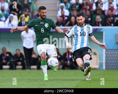 Lionel messi passa la palla mentre il difensore saudita Abdulelah al-Malki preme con forza per forzare un turnover argentino durante la Coppa del mondo FIFA 2022 Foto Stock