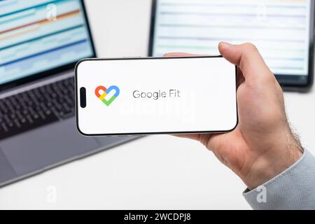 Logo Google Fit dell'app sullo schermo del telefono cellulare tenuto dall'uomo davanti al laptop e al tablet, dicembre 2023, Praga, Repubblica Ceca Foto Stock