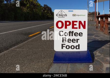 Indicazioni stradali per il bar e ristorante della chiesa che pubblicizza caffè, birra, cibo a Manapouri, Aotearoa (nuova Zelanda), Waipounamu (Isola del Sud) Foto Stock