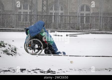 Amburgo, Germania. 15 gennaio 2024. Un uomo siede su una sedia a rotelle ad August-Bebel-Park di fronte al Drob Inn, con la neve intorno a lui. Il centro di consulenza antidroga vicino alla stazione ferroviaria principale dispone di sale integrate per il consumo di droga. Credito: Rabea Gruber/dpa/Alamy Live News Foto Stock