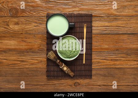 Tazza di tè matcha fresco, polvere e accessori su fondo di legno Foto Stock